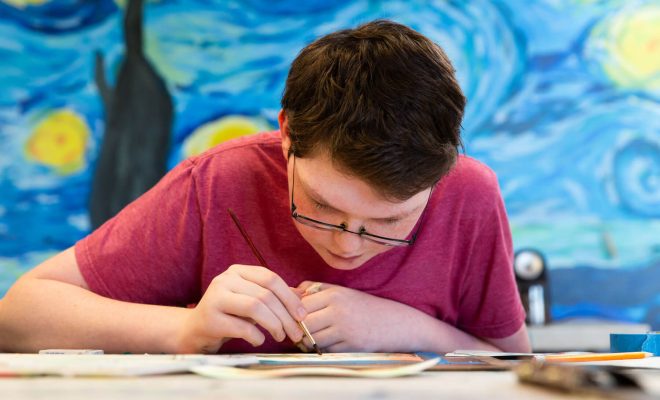 A boy focusing intently on a art project in a studio setting.