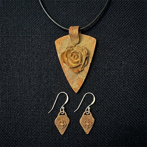 Handmade pendant necklace with a carved rose design.