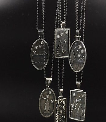 Metal engraved pendant necklaces on display.
