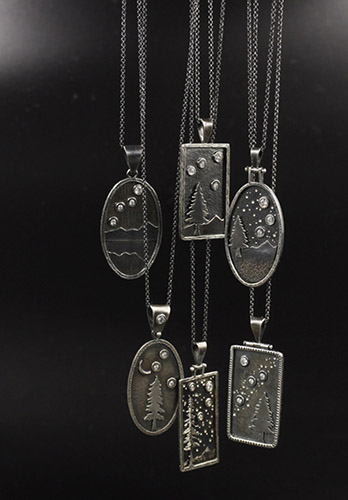 Metal engraved pendant necklaces on display.