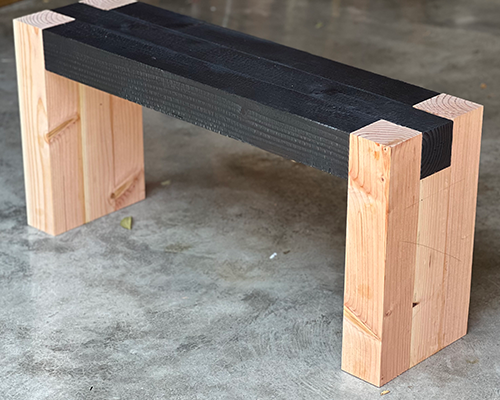 Modern wooden bench with a dark seat.