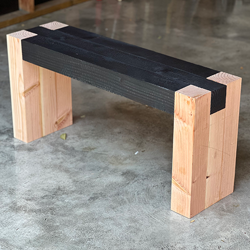 Modern wooden bench with a dark seat.