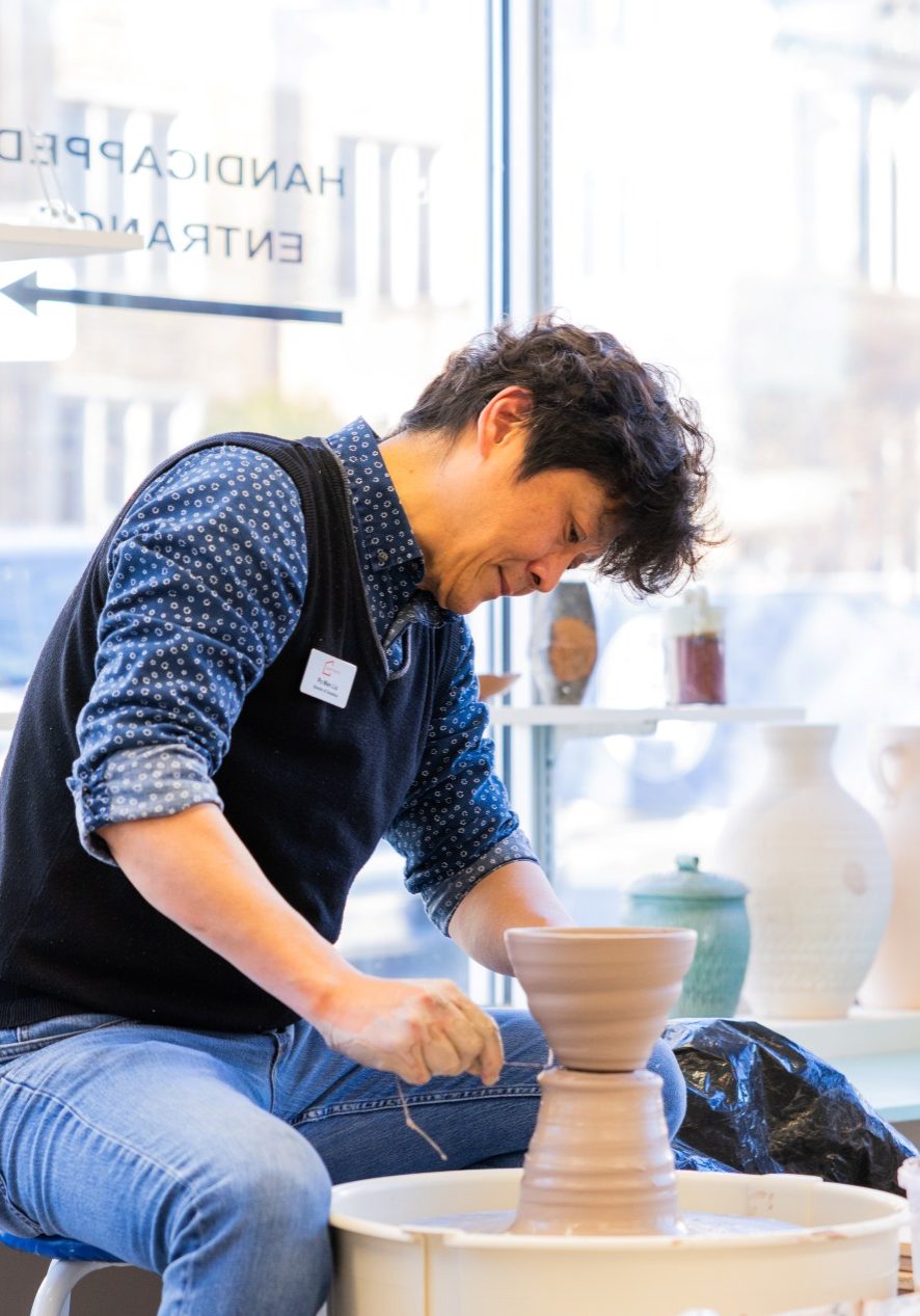 Person shaping clay on a pottery wheel.