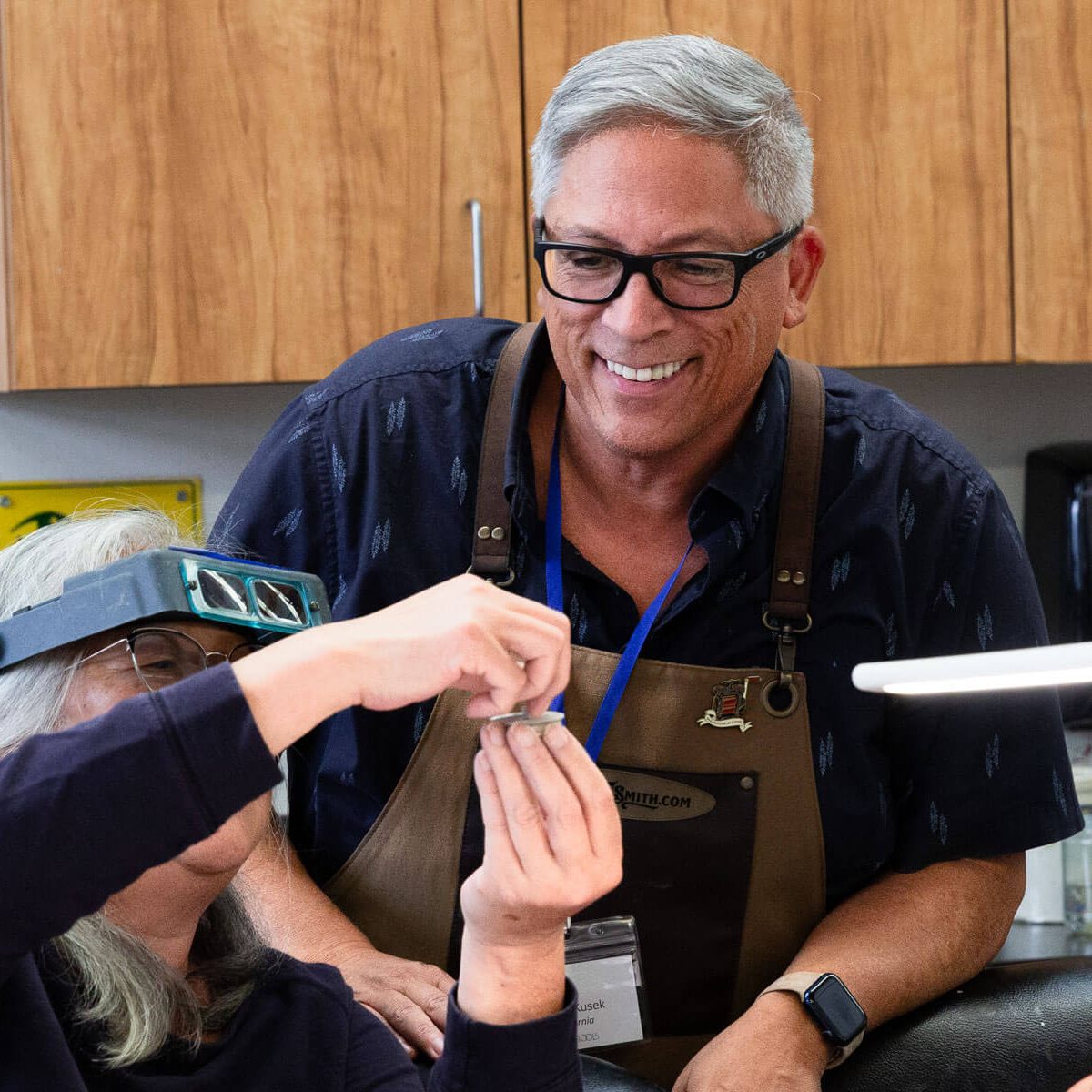 An instructor assisting a student with jewelry making in a studio
