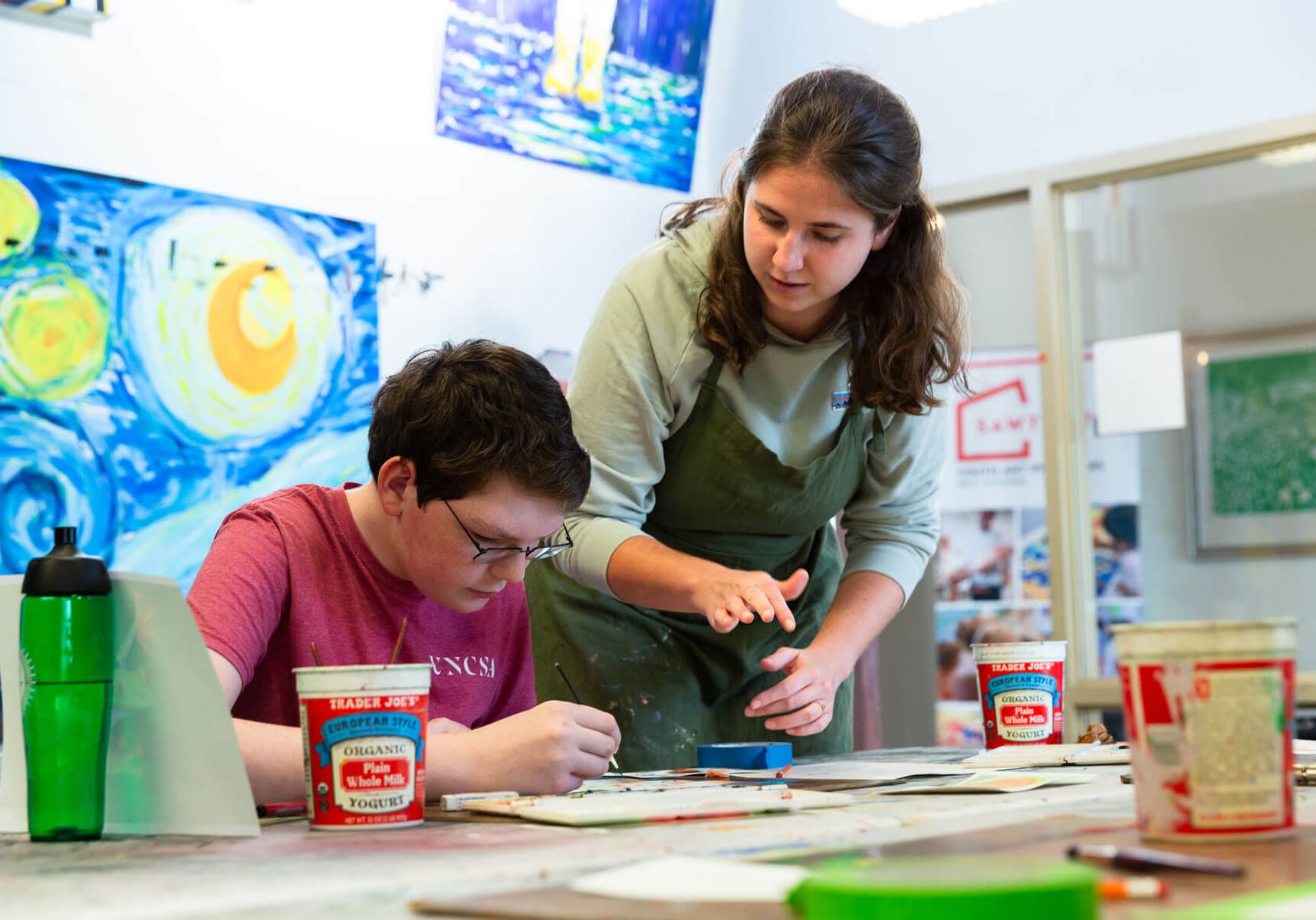 An instructor assisting a student with an artwork project.