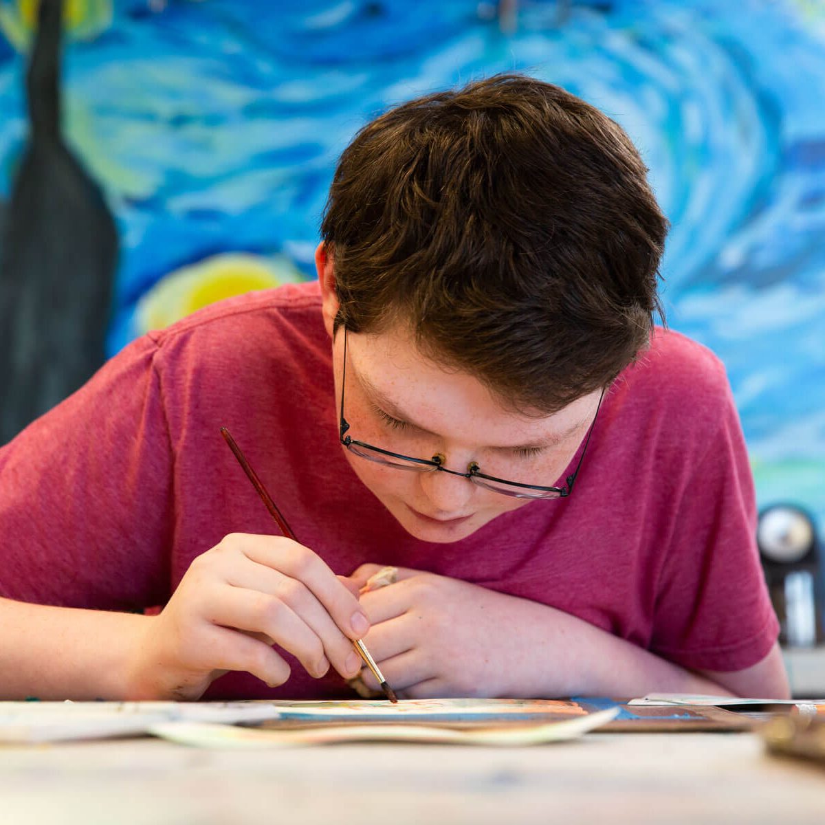 A boy focusing intently on a art project in a studio setting.