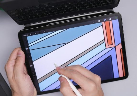 Hands using a stylus to draw digital art on a tablet.